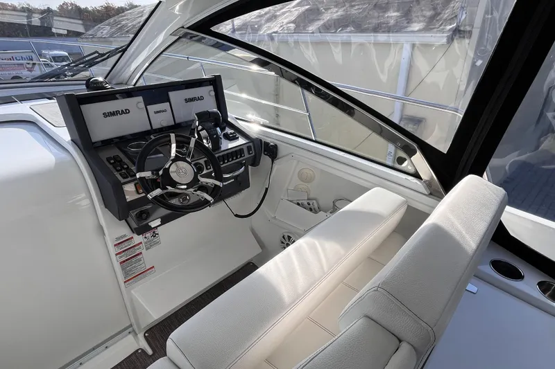 Slide: The Image of 2018 Cruisers Yachts 390 Express Coupe helm with Simrad navigation system and white seating. - 3