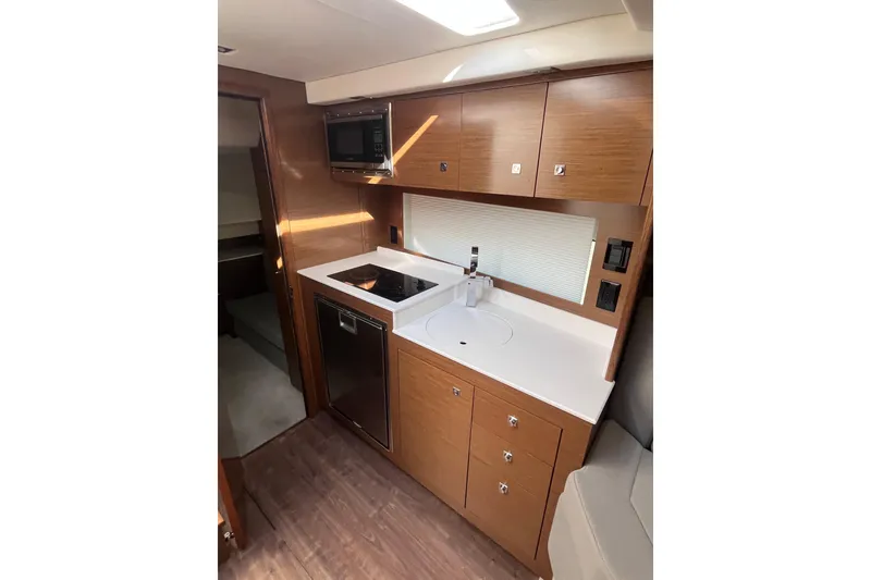 Slide: The Image of 2018 Cruisers Yachts 390 Express Coupe kitchen with modern appliances and wood cabinetry. - 5