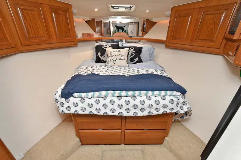 Slide: The Image of 1997 Viking 47 Convertible yacht bedroom with cozy bedding and wooden cabinetry. - 25