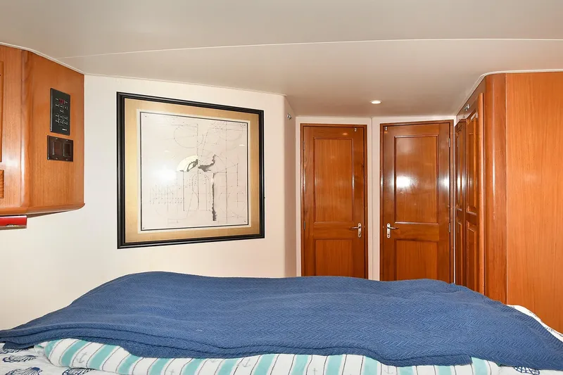 Slide: The Image of Cozy bedroom interior of 1997 Viking 47 Convertible yacht with wooden cabinets and framed artwork. - 27