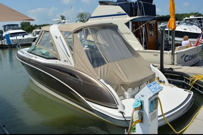 Slide: The Image of 2015 Formula 310 Sun Sport boat docked at marina, featuring beige canopy and sleek design. - 1