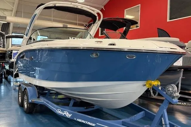 The Image of 2026 Sea Ray SDX 230 boat on trailer, blue hull, parked outside dealership. - 1