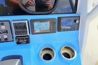 Slide: The Image of 2021 Tidewater 272 CC Adventure boat dashboard with electronic controls and cup holders. - 12