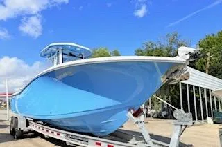 Slide: The Image of 2021 Tidewater 272 CC Adventure boat on trailer under blue sky. - 2