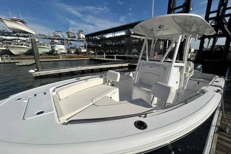 Slide: The Image of 2025 Sea Hunt Ultra 229 boat docked at marina, showcasing sleek design and spacious seating. - 13