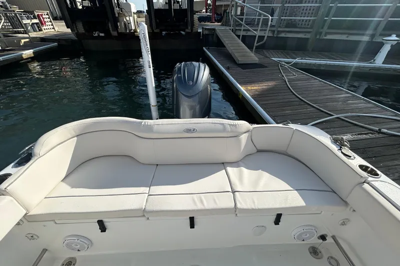 Slide: The Image of 2025 Sea Hunt Ultra 229 boat with cushioned seating at a marina dock. - 15