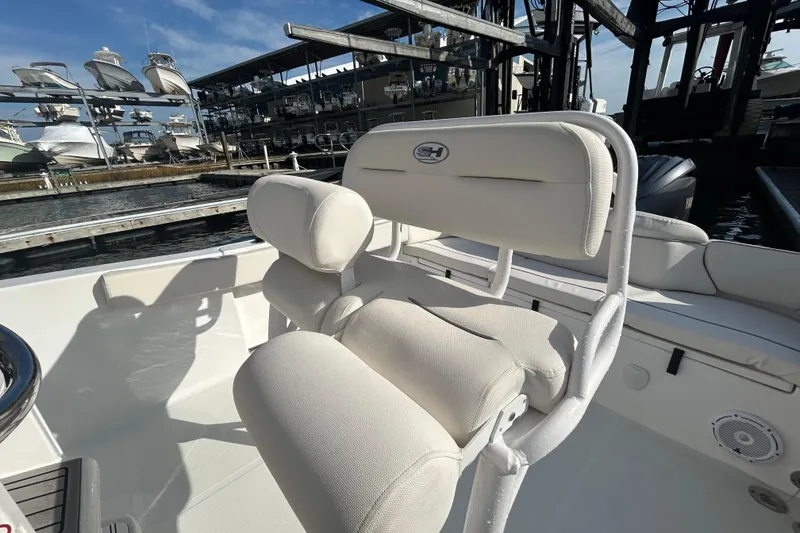 Slide: The Image of 2025 Sea Hunt Ultra 229 boat interior with white cushioned seating at marina. - 16