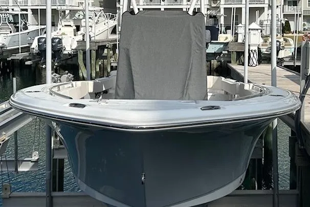 Slide: The Image of 2025 Sea Hunt Ultra 229 boat on water near marina, clear sky background. - 3