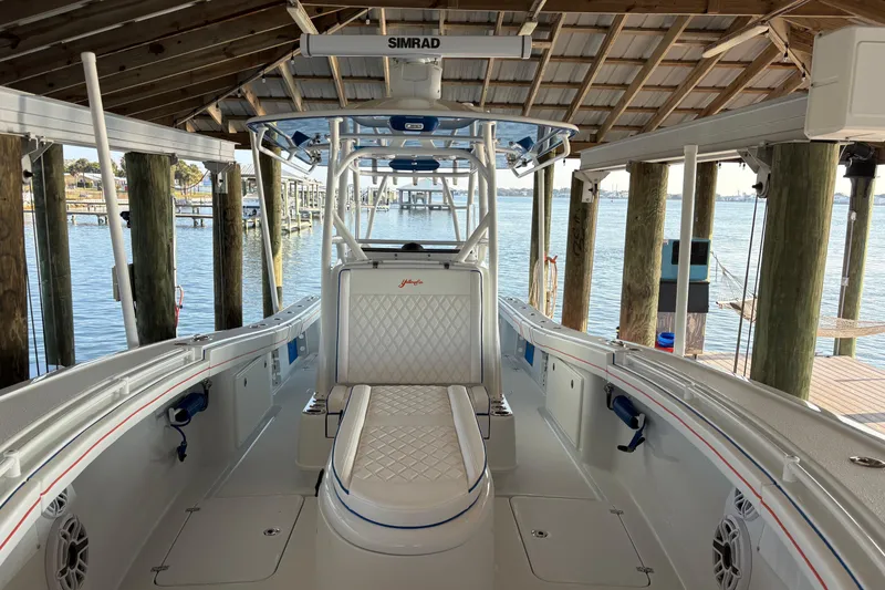 Slide: The Image of 2024 Yellowfin 36 Offshore boat docked under a wooden canopy, featuring a sleek interior design. - 13