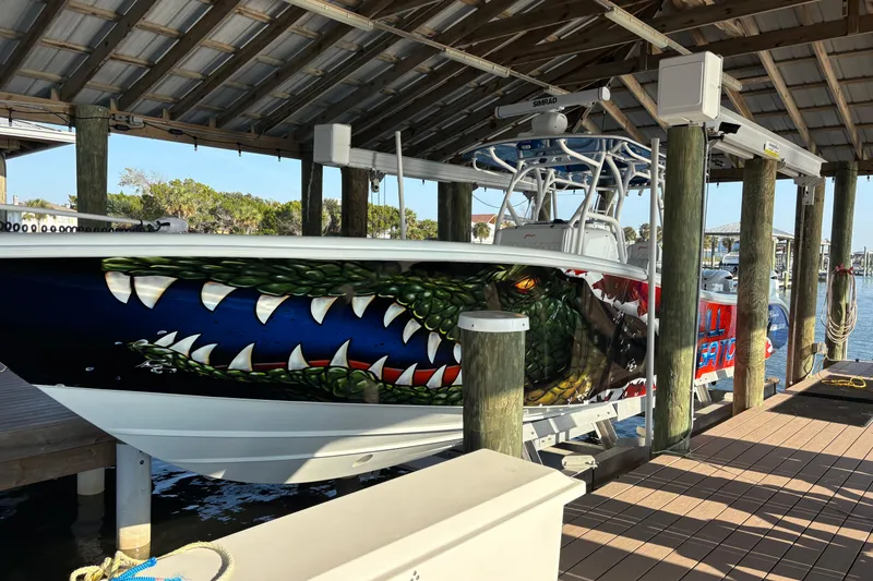 Slide: The Image of 2024 Yellowfin 36 Offshore boat with striking alligator-themed hull art in a marina. - 2