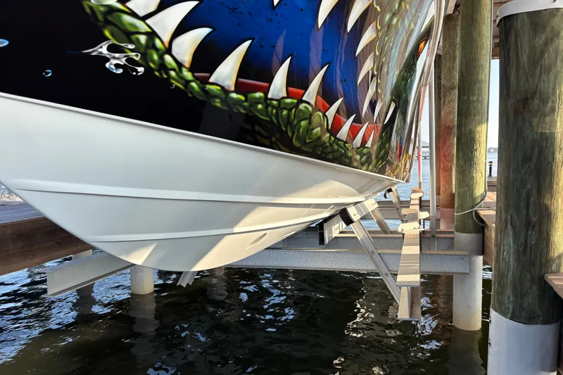 Slide: The Image of 2024 Yellowfin 36 Offshore boat with vibrant shark-themed hull design on a lift. - 5