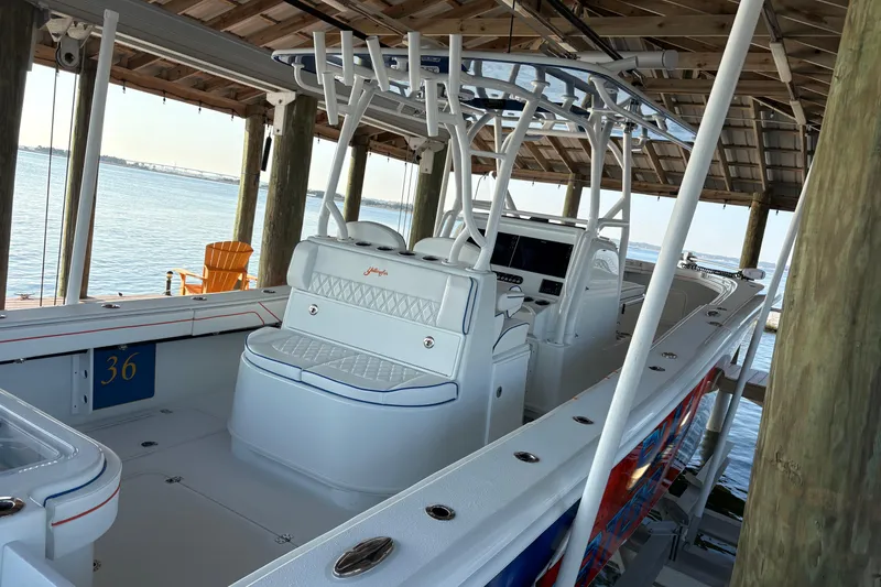 Slide: The Image of 2024 Yellowfin 36 Offshore boat docked under a wooden shelter by the water. - 9