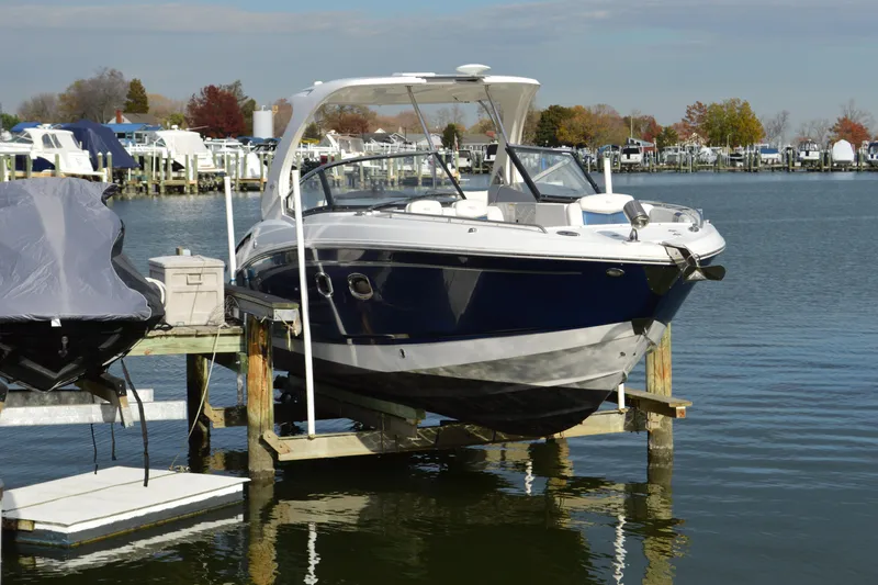 Slide: The Image of 2013 Chaparral 327 SSX boat docked at a marina, surrounded by calm water. - 1