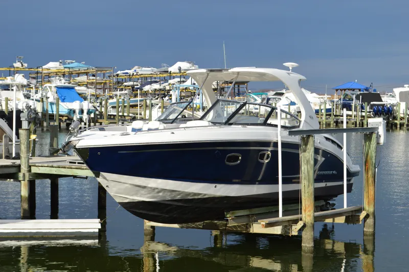 Slide: The Image of 2013 Chaparral 327 SSX boat docked at a marina, surrounded by other vessels. - 2