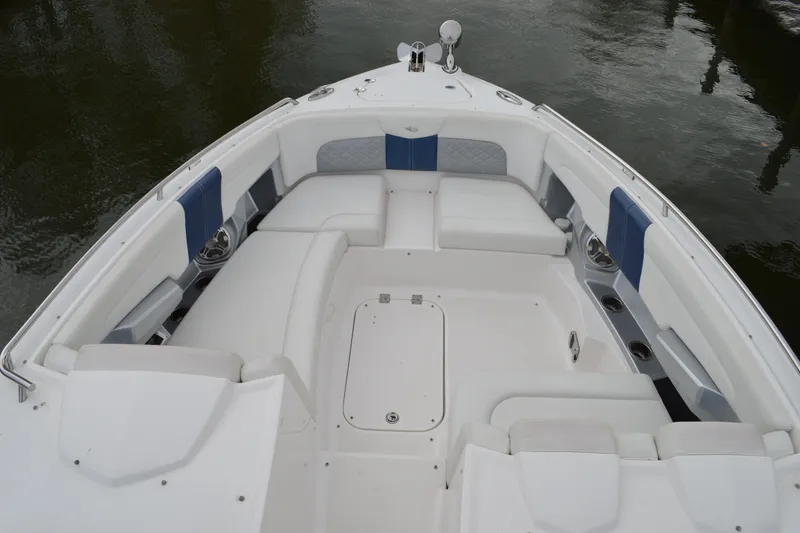 Slide: The Image of 2013 Chaparral 327 SSX boat interior with white and blue seating, docked on water. - 9