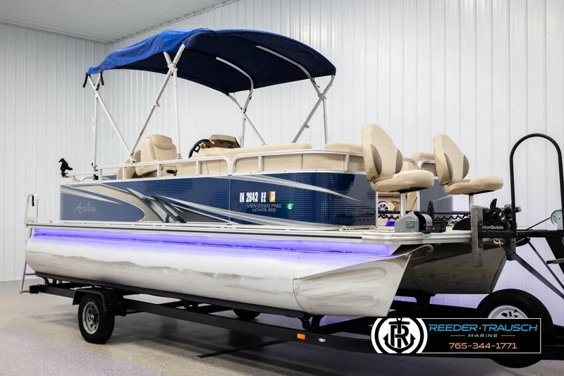 Slide: The Image of 2020 Avalon VEN FNC pontoon boat with blue canopy and trailer in showroom. - 3
