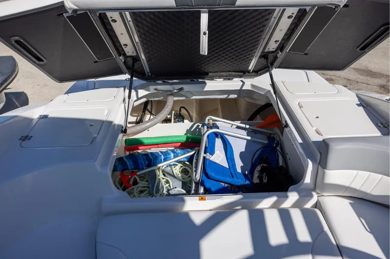 Slide: The Image of 2022 Chaparral 23 SSi OB boat storage compartment with various boating accessories. - 12
