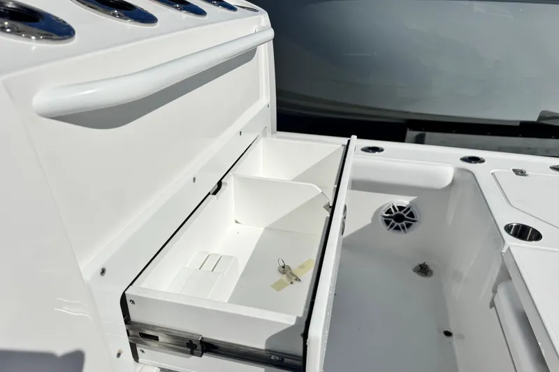 Slide: The Image of 2026 Caymas 28 HB boat storage compartment with open drawer and cup holders. - 13