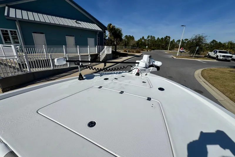 Slide: The Image of 2026 Caymas 28 HB boat deck near a blue building and parked vehicles. - 26