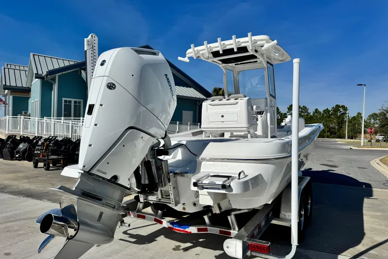 Slide: The Image of 2026 Caymas 28 HB boat with powerful outboard motor on trailer, parked near coastal building. - 6