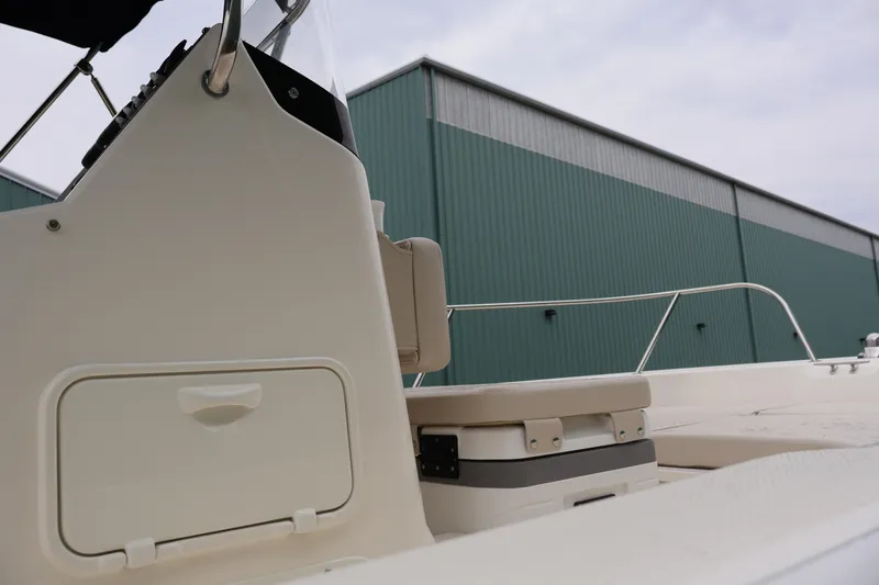 Slide: The Image of 2026 Boston Whaler 190 Montauk boat interior with console and seating, near green building. - 18