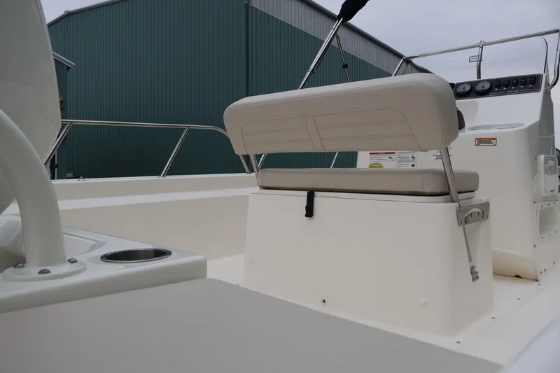 Slide: The Image of 2026 Boston Whaler 190 Montauk boat interior with seating and console, docked near a green building. - 24