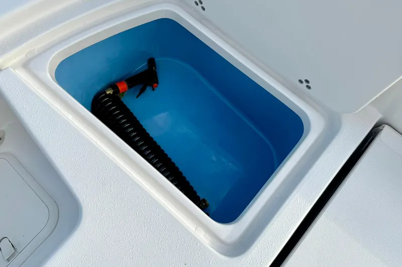 Slide: The Image of Livewell compartment in 2026 Carolina Skiff 26 Ultra Elite boat, featuring a coiled hose. - 41