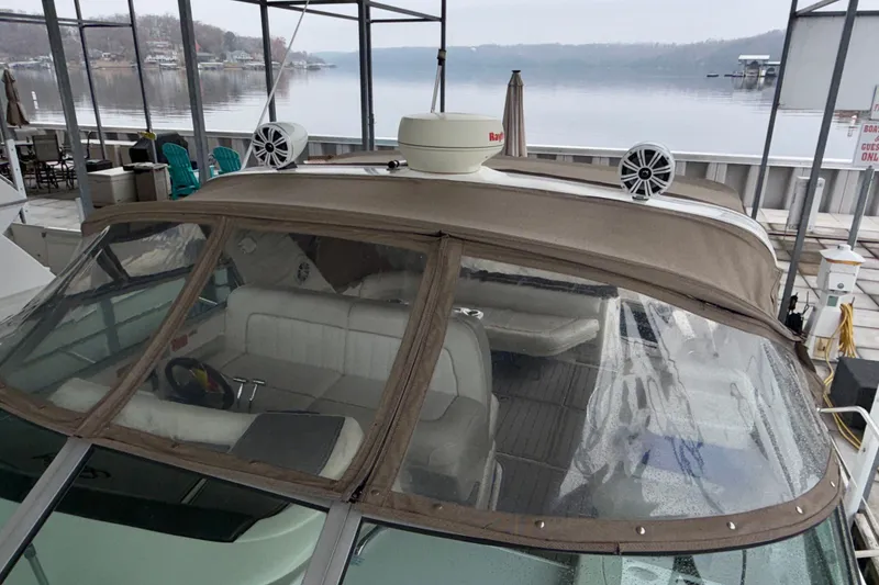 Slide: The Image of 1995 Sea Ray 370 Sundancer docked, featuring a covered cockpit and lake view. - 6