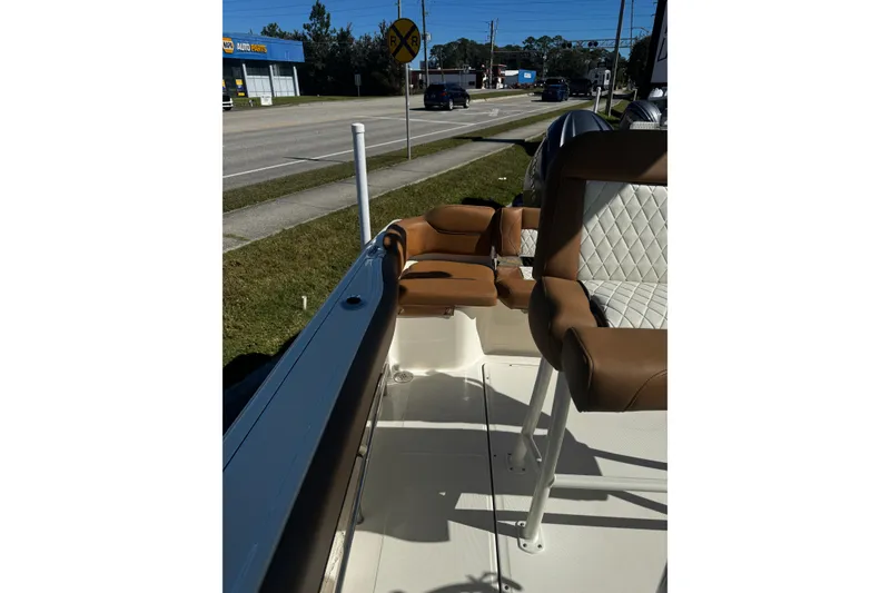 Slide: The Image of 2026 Pioneer 222 Islander boat interior with tan and white seating, parked near a road. - 18