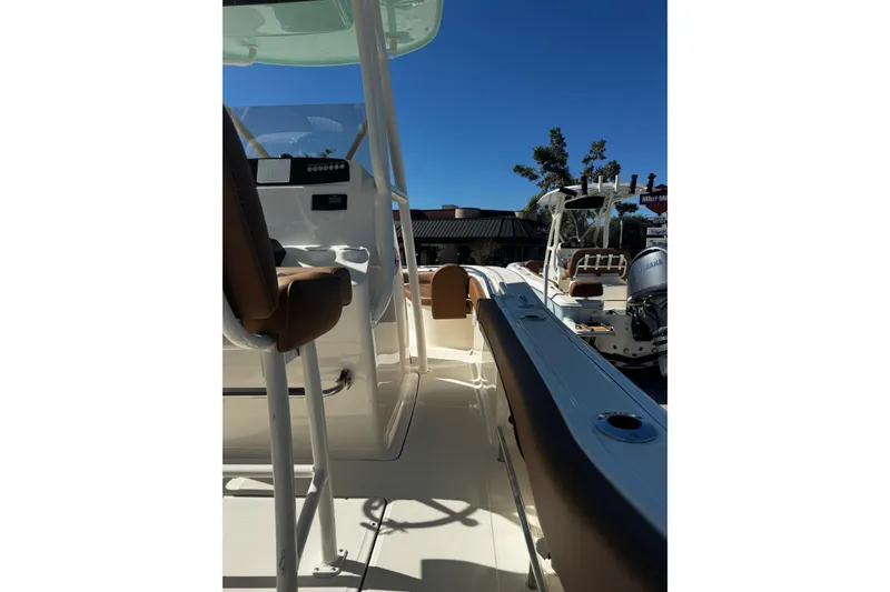 Slide: The Image of 2026 Pioneer 222 Islander boat interior with seating and console, under clear blue sky. - 19