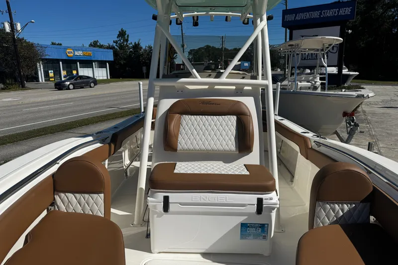 Slide: The Image of 2026 Pioneer 222 Islander boat interior with brown and white seating, parked near auto parts store. - 28