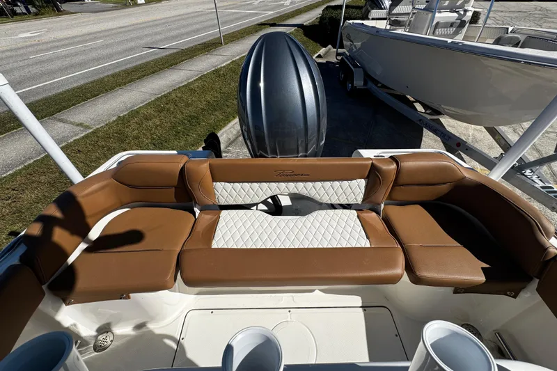 Slide: The Image of 2026 Pioneer 222 Islander boat with brown and white seating, docked near a road. - 36