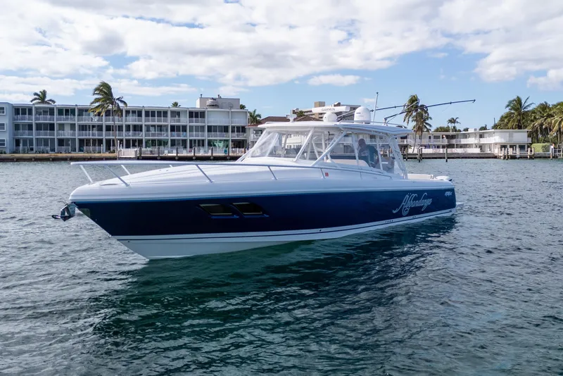 Slide: The Image of 2019 Intrepid 407 Cuddy boat on water near waterfront buildings and palm trees. - 14