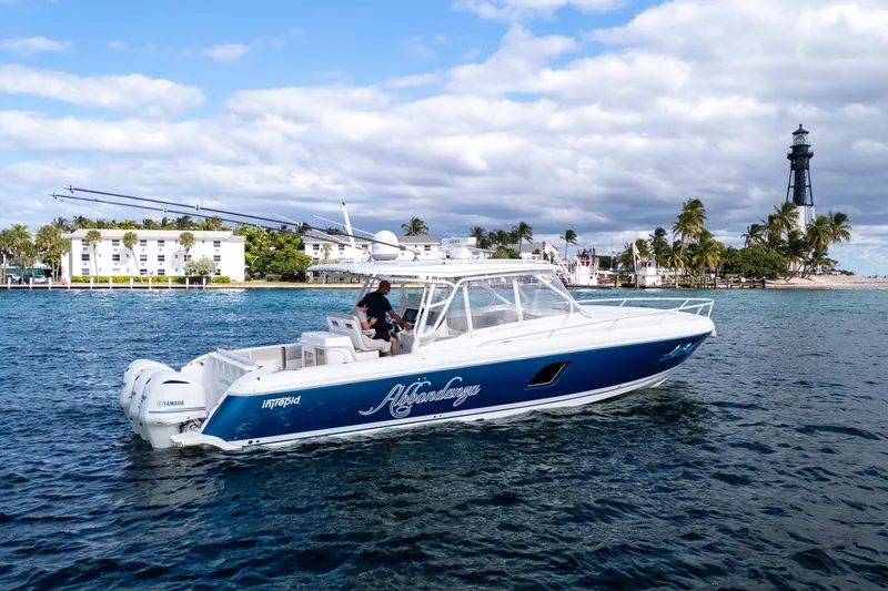 Slide: The Image of 2019 Intrepid 407 Cuddy boat cruising near a lighthouse and palm trees. - 16