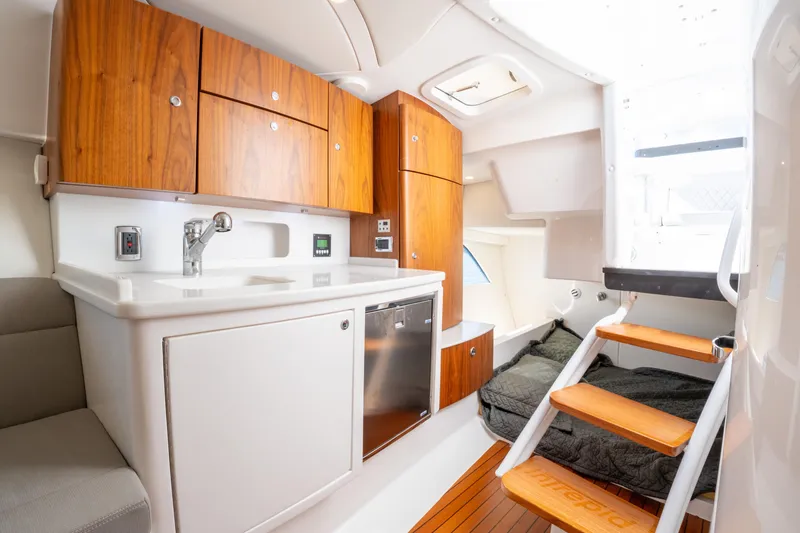 Slide: The Image of 2019 Intrepid 407 Cuddy interior with kitchenette, wooden cabinets, and cozy sleeping area. - 33