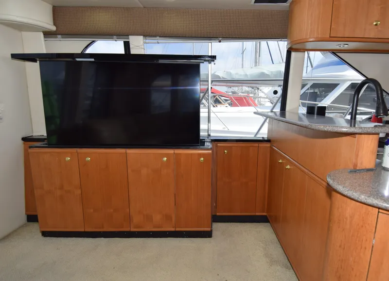Slide: The Image of Interior of 1999 Bayliner 5288 yacht with wooden cabinetry and large TV. - 5