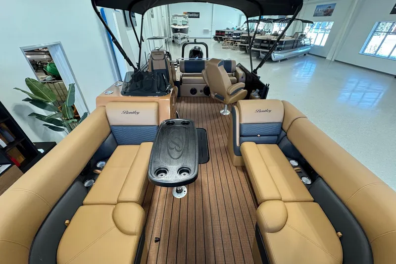 Slide: The Image of 2026 Bentley Pontoons Elite 223 Swingback interior with tan seating and wood-style flooring. - 10