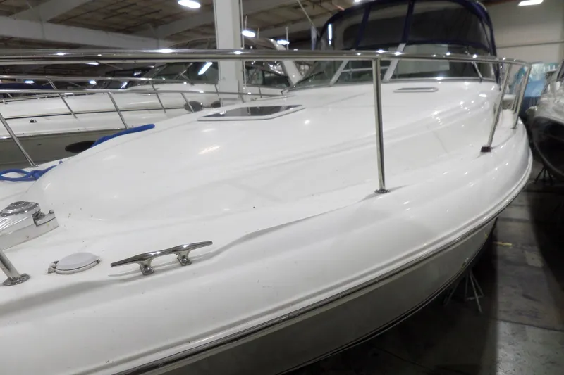 Slide: The Image of 2000 Sea Ray 340 Sundancer boat in indoor storage, showcasing sleek white deck design. - 2