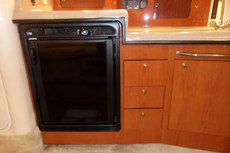 Slide: The Image of Interior of 2000 Sea Ray 340 Sundancer with wooden cabinetry and compact refrigerator. - 48