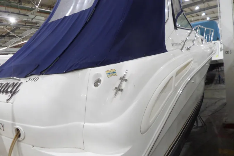 Slide: The Image of 2000 Sea Ray 340 Sundancer boat with blue cover in a storage facility. - 8