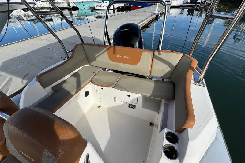 Slide: The Image of 2022 Zodiac Medline 6.8 boat interior with cushioned seating at a marina. - 11