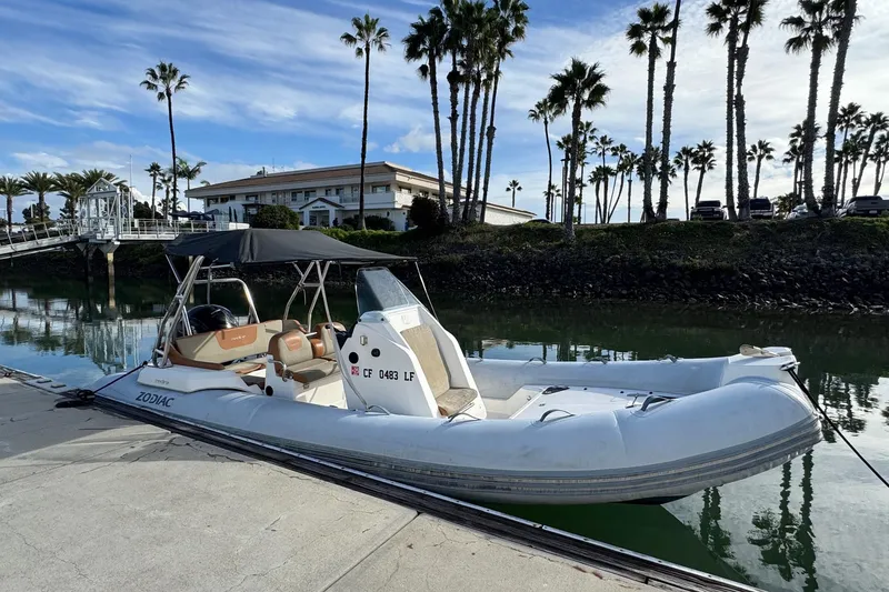 Slide: The Image of 2022 Zodiac Medline 6.8 boat docked by palm trees and waterfront building. - 2