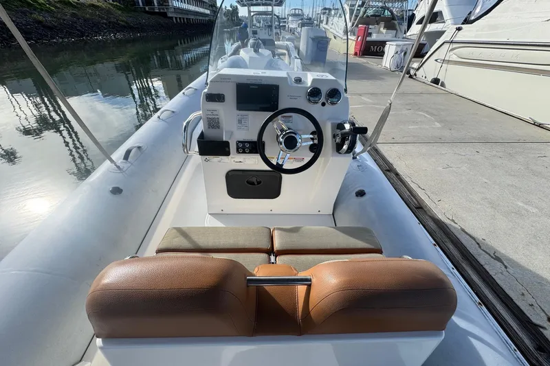 Slide: The Image of 2022 Zodiac Medline 6.8 boat interior with steering console and seating, docked by the water. - 24