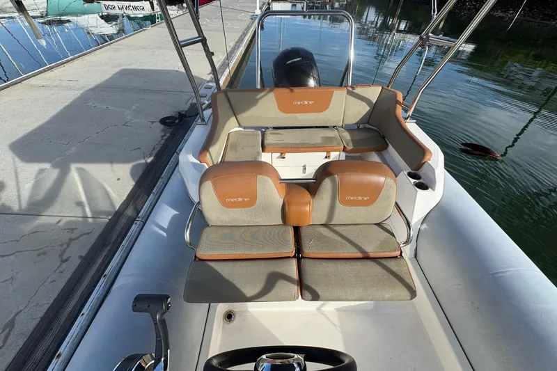 Slide: The Image of 2022 Zodiac Medline 6.8 boat interior with cushioned seating and steering wheel. - 30