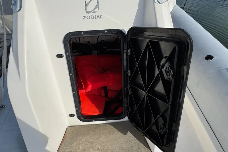 Slide: The Image of 2022 Zodiac Medline 6.8 boat storage compartment with red life jackets inside. - 36