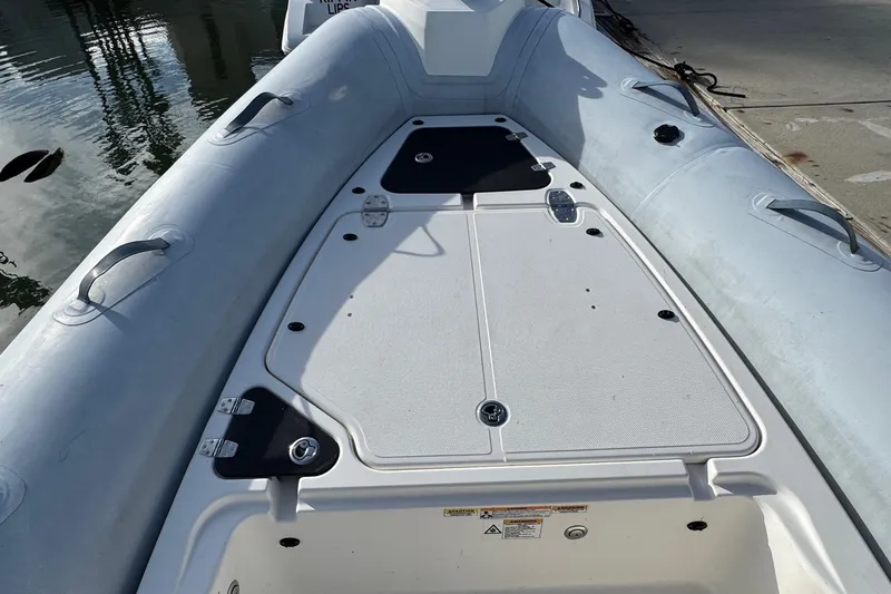 Slide: The Image of 2022 Zodiac Medline 6.8 boat deck with storage compartments, docked by the water. - 37