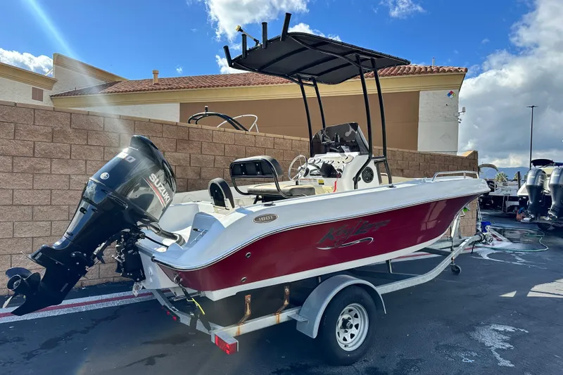 Slide: The Image of 2021 Key Largo 1801 boat on trailer, parked outdoors with mountains in background. - 2