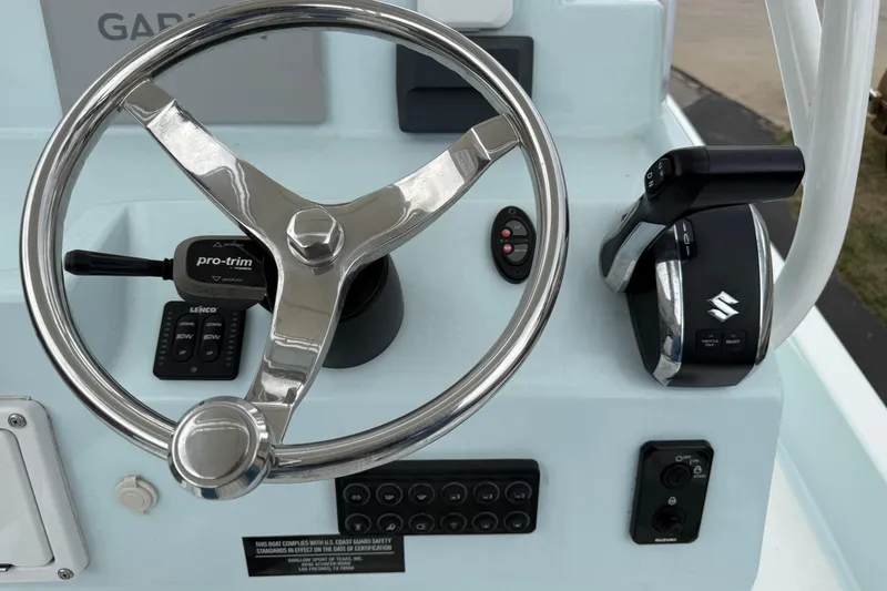 Slide: The Image of Steering console of 2023 Shallow Sport 25 X3 boat with controls and Suzuki throttle. - 10