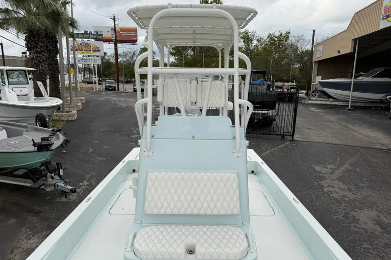 Slide: The Image of 2023 Shallow Sport 25 X3 boat with white seating, parked at a marina. - 22