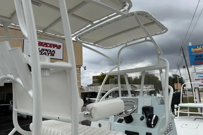 Slide: The Image of 2023 Shallow Sport 25 X3 boat interior with steering console and seating, under cloudy sky. - 28